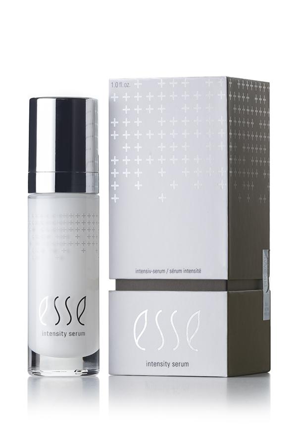 A sleek bottle of Esse Intensity Serum stands next to its matching box. The bottle is pristine white, adorned with a black cap and subtle silver accents, while the box features a clean white and gray palette with an elegant minimalist design. The product name, "Esse Intensity Serum," is prominently displayed on both items.